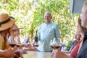 Ross Halleck shares his acclaimed estate grown Pinot Noir at a wine tasting for guests on the deck at Halleck Vineyard.