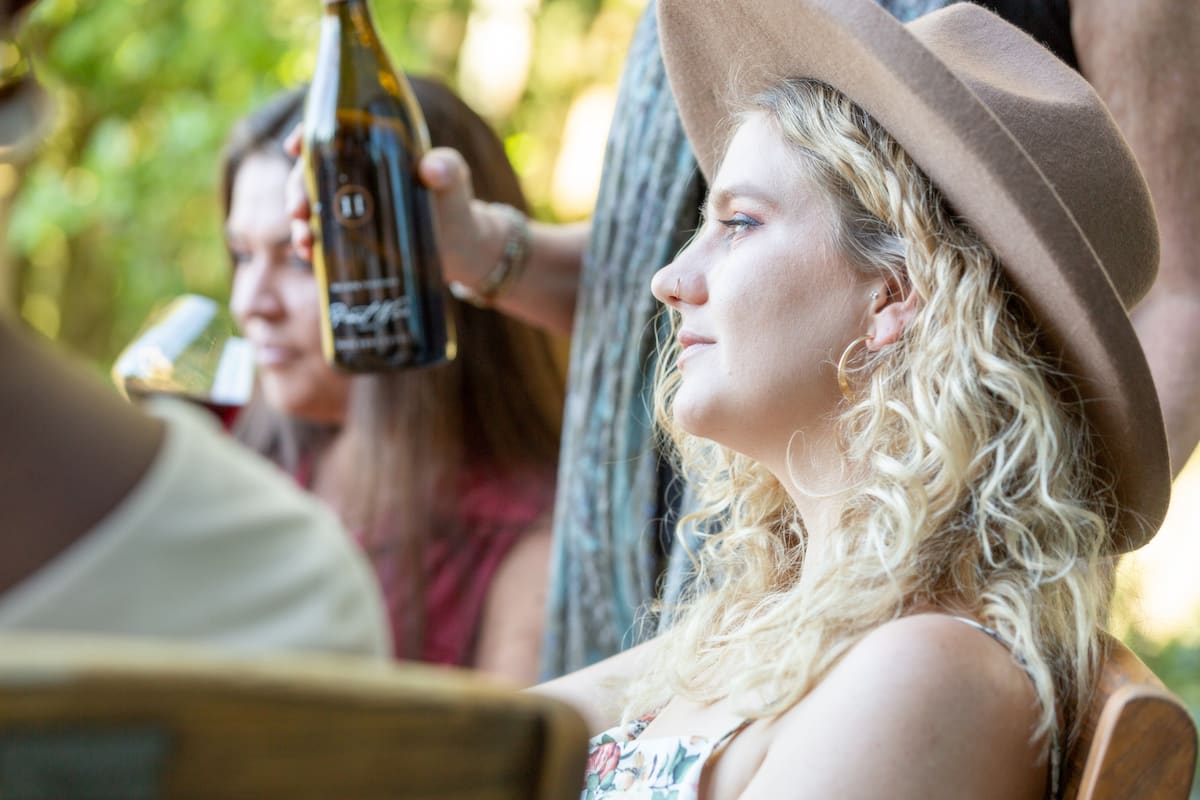 A young woman is savoring a serene wine tasting experience on the deck of a winery estate in Sonoma County, enjoying a crisp glass of Sauvignon Blanc while overlooking the lush Rissuain River Valley and the majestic Mount Helena of Napa Valley. The map of the wine country in Sonoma Valley and Napa Valley is on display in the tasting room, showcasing the nearby vineyards and wineries. The valley below is dotted with charming hotels, restaurants, and tasting rooms, offering a plethora of wine experiences for visitors to explore. The estate's garden is adorned with colorful flowers, adding to the tranquil atmosphere. The winery's cellars and caves offer a glimpse into the art of winemaking, and the menu offers a variety of white and Pinot Noir wines from Sonoma County and beyond. This idyllic setting is just a short drive from San Francisco, making it a popular destination for Bay Area wine enthusiasts seeking to indulge in Sonoma wine.