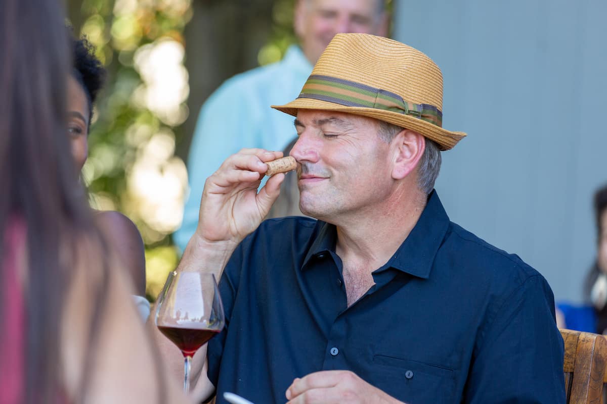 At the wine tasting event held at the Sebastopol winery vineyard estate, a male wine enthusiast is seen smelling the cork of a bottle of Sonoma Coast Pinot Noir. The aroma of the wine fills the air as he takes in the scent, examining it closely before taking a sip. The estate is nestled in the heart of California's Sonoma County Wine Country, surrounded by vineyards and wineries that dot the landscape. It's a picturesque setting, with the rolling hills of the Sonoma Valley providing a stunning backdrop to the event. The winery is just a short drive from Napa and San Francisco, making it an easy destination for those looking to experience the best of California wine country. As the enthusiast savors the wine, he takes in the flavors and notes that make it unique, adding it to his list of favorites from the region.