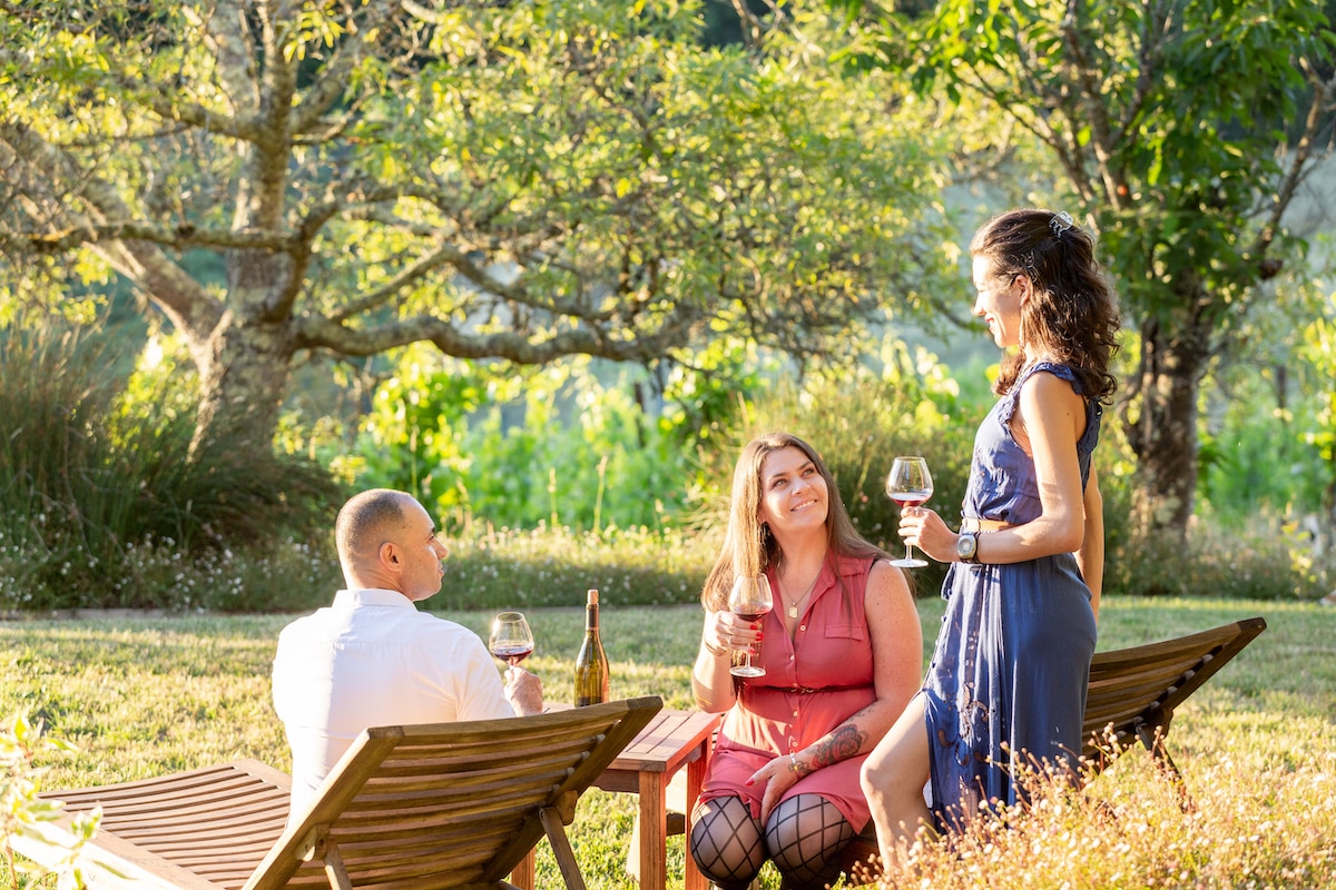 Two women and a man are celebrating and enjoying the beautiful grounds of a Sebastopol winery vineyard estate, with glasses of the reserved pinot noir in hand. The experience is one of a kind, with the opportunity to tour the vineyards and celebrate the beauty of the Napa and Sonoma Valley wine regions. The group savors the full-bodied flavor of the pinot noir, taking in the aromas and appreciating the complex taste. The winery's dedication to their vineyards and the winemaking process is evident in the quality of the wines they produce. With the perfect setting to enjoy a glass of wine, it's a place that visitors will want to reserve for future visits to the Napa and Sonoma wine country.