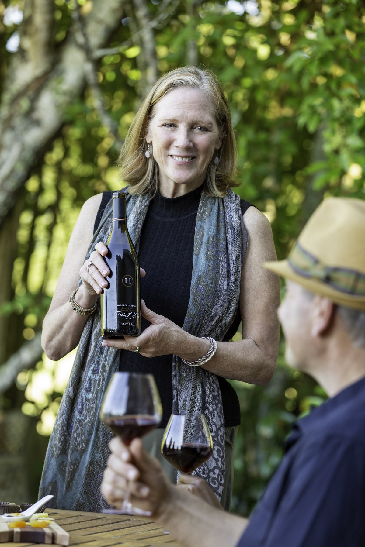 At the wine tasting event at the Sebastopol winery vineyard estate, winegrower Jennifer Halleck presents her double gold Sonoma Coast Pinot Noir to the guests. She shares the story behind the wine's creation and its unique characteristics, highlighting the efforts of the winery to produce high-quality wines in the Sonoma County Wine Country. As guests sip the Pinot Noir, they admire the beautiful vineyard surroundings and the delicious flavors of the wine. Halleck answers their questions and provides a memorable experience that showcases the best of California's wine industry.